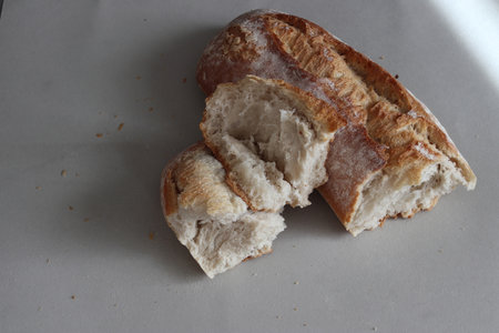 A broken freshly baked rustic baguette. It is located on a gray background. Close-up.の写真素材