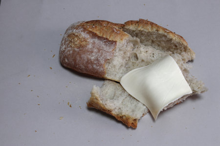 A broken freshly baked rustic baguette with melted cheese. It is located on a gray background. Close-up.の写真素材