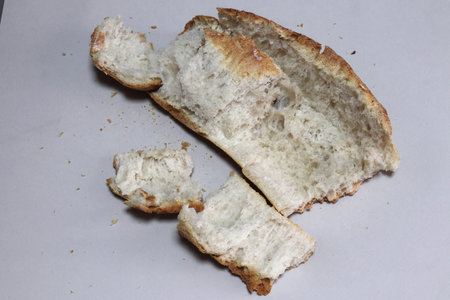 A broken freshly baked rustic baguette. It is located on a gray background. Close-up.の写真素材