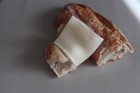 A broken freshly baked rustic baguette with melted cheese. It is located on a gray background. Close-up.の写真素材