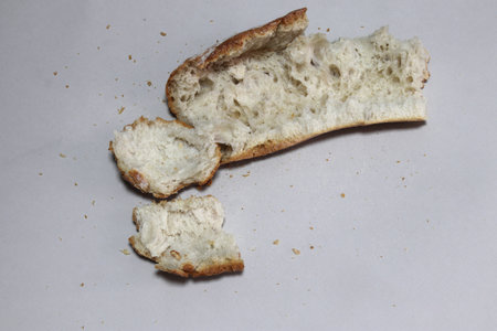 A broken freshly baked rustic baguette. It is located on a gray background. Close-up.の写真素材