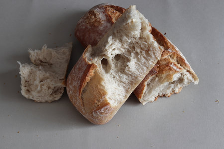 A broken freshly baked rustic baguette. It is located on a gray background. Close-up.の写真素材