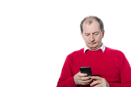 Portrait of a sixty-year-old man in a red pullover. Isolated over white background. Close-up.の写真素材