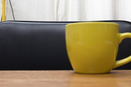 The yellow cup is located on a wooden surface. The background is made of black artificial leather. Close-up. The cup is blurred.の写真素材