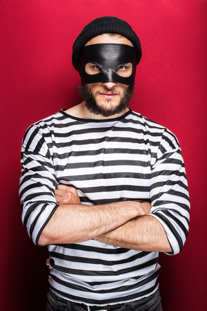 Angry thief with mask on red background   の写真素材