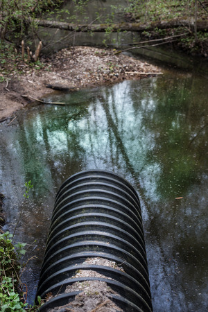 Dirty water stems from the pipe polluting the river   の写真素材