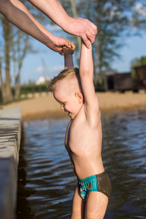 Father helps son to climb on the footbridge   の写真素材