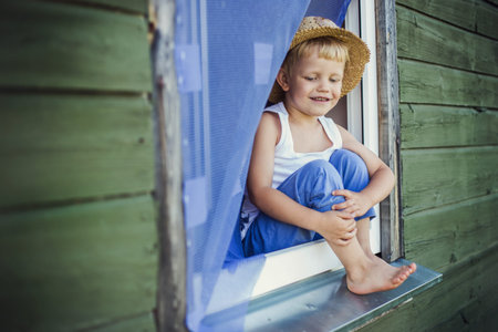 Outdoor portrait: Young boy sit on the window sill  
