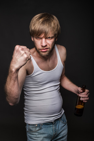 Drunk man threaten with fist. Studio portrait over black backgroundの写真素材