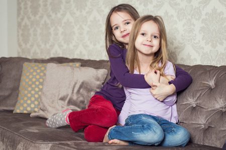Portrait of two cute sisters at home. Family. Indoor lifestyle portrait of couple beautiful sisters best friends. Cozy home atmosphereの写真素材
