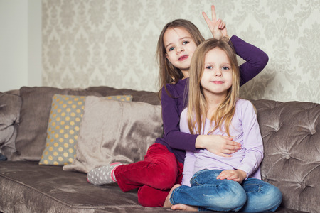 Portrait of two cute sisters at home. Family. Indoor lifestyle portrait of couple beautiful sisters best friends. Cozy home atmosphereの写真素材
