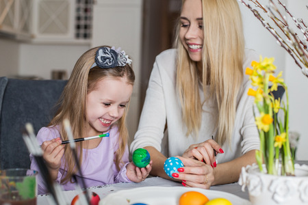 Loving mother and her daughter painting easter eggs. Cozy home atmosphere. Easterの写真素材