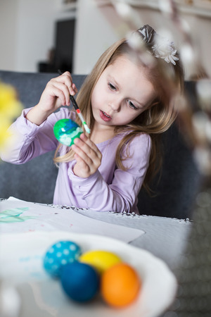A happy little kid coloring easter eggs. Cozy home atmosphere. Easterの写真素材