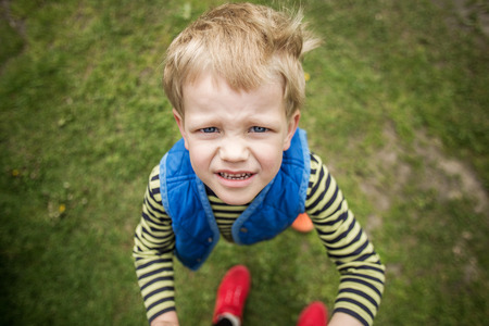 Naughty boy looking up. Outdoor portrait. Close upの写真素材
