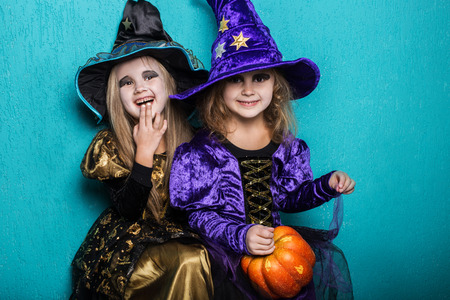 Girls in a suit of a witch. Halloween. Fairy. Tale. Studio portrait on blue backgroundの写真素材