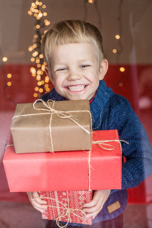 Smiling funny child holding Christmas gift in hand. Christmas concept. Birthdayの写真素材