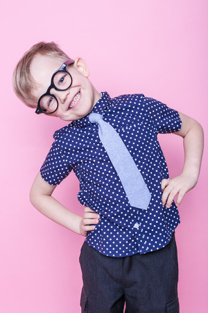 Stylish boy in shirt and glasses with big smile. School. Preschool. Fashion. Studio portrait over pink backgroundの写真素材