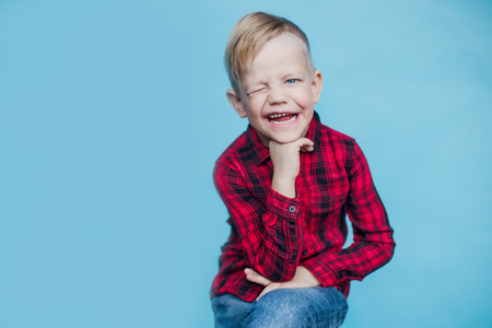 Fashionable little kid with red shirt. Fashion. Style. Studio portrait over blue backgroundの写真素材