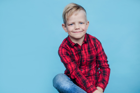 Fashionable little kid with red shirt. Fashion. Style. Studio portrait over blue backgroundの写真素材