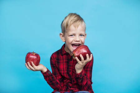 Handsome little kid with fruits. Studio portrait over blue backgroundの写真素材