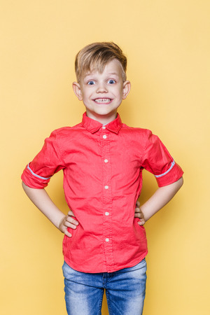 Little fashionable child with pink shirt. Fashion model. Spring. Summer. Studio portrait over yellow backgroundの写真素材