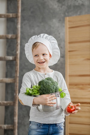 Handsome beautiful boy holding a pot full of vegetables. Healthy food. Harvest. Little chefの写真素材