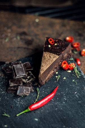 Piece of dark chocolate cake with red hot pepper. The restaurant or cafe atmosphere. Retro. Vintageの写真素材