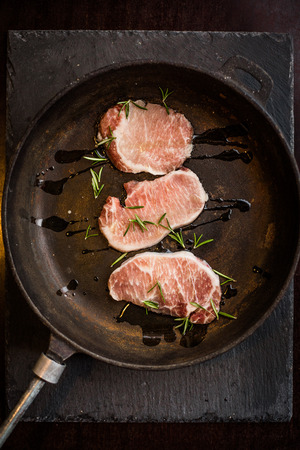 Raw ribeye beef steak with rosemary on pan. Top view. Restaurantの写真素材
