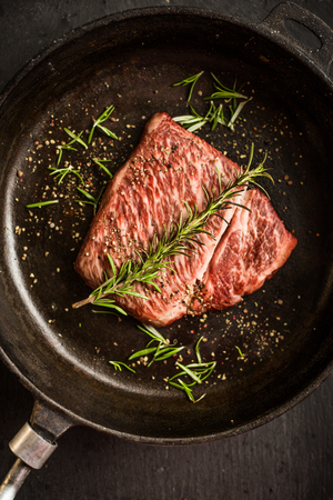Close up raw wagyu beef striploin steak with pepper on dark pan. Restaurantの写真素材