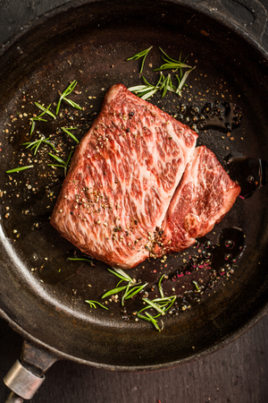 Close up raw wagyu beef striploin steak with pepper on dark pan. Restaurantの写真素材