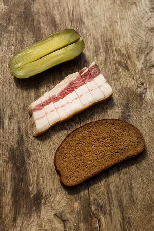 Bacon, bread and cucumber over wooden background. Russian and ukrainian traditional appetizerの写真素材