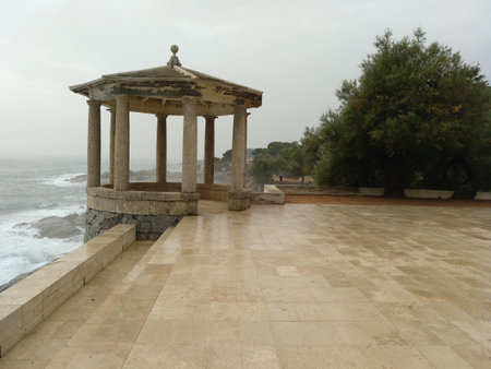 Beautiful temple, stone gazebo with columns facing the sea, on a humid and foggy dayの写真素材