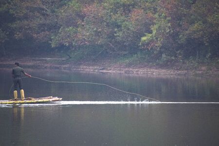 Bamboo rafting by a man in river with ropeの写真素材