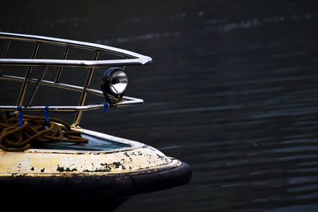 Bow of boat in river with ropes resting in front on boatの写真素材