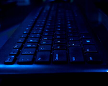 Black keyboard keys with ultra violet blue light effectの写真素材