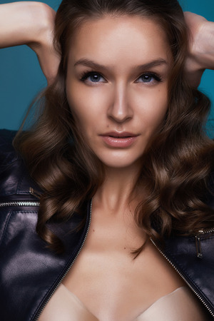 Portrait of the beautiful girl with shining tanned skin and Big Blue Bright eyes and curly hair on a blue background and cover her ears cause donの写真素材