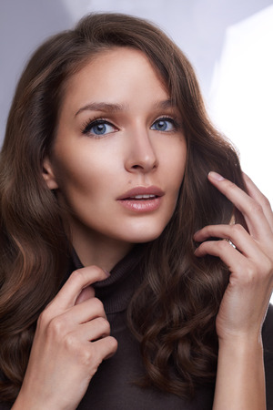 Portrait of a young girl with perfect skin and makeup, with curly dark hair looking at the cameraの写真素材