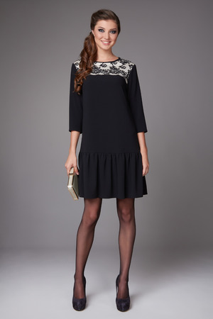 Beautiful sexy young business woman with evening make-up wearing a dress and high-heeled shoes and a small black handbag, business clothes for meetings and walks autumn collectionの写真素材