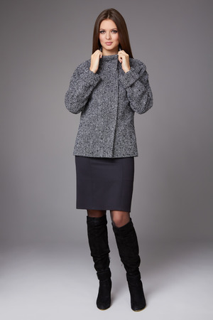 Beautiful sexy young business woman with evening make-up wearing a skirt to the knee wool coat jacket high svpogi high heels and a small black handbag, business clothes for meetings and walks autumn collectionの写真素材