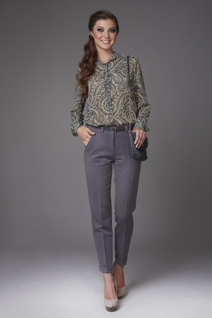 Beautiful sexy young business woman with evening make-up dressed in tight pants and silk blouse with lace long sleeves and high-heeled shoes and a small black handbag, business clothes for meetings and walksの写真素材