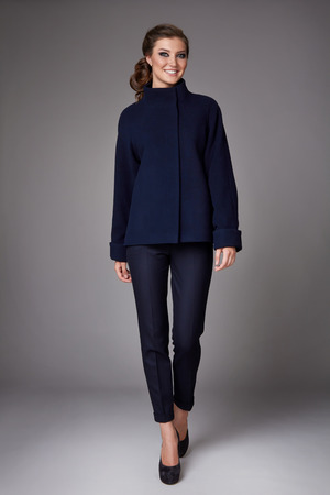 Beautiful sexy attractive young woman with dark hair wearing a strict business suit black skinny pants short coat with wide sleeves black high-heeled shoes clothes for autumn walks business meetingの写真素材