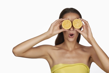 Beautiful sexy young woman wit perfect healthy skin and long brown hair day makeup bare shoulders holding orange lemon grapefruit healthy eating organic food diet weight lossの写真素材