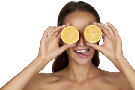 Beautiful sexy young woman wit perfect healthy skin and long brown hair day makeup bare shoulders holding orange lemon grapefruit healthy eating organic food diet weight lossの写真素材