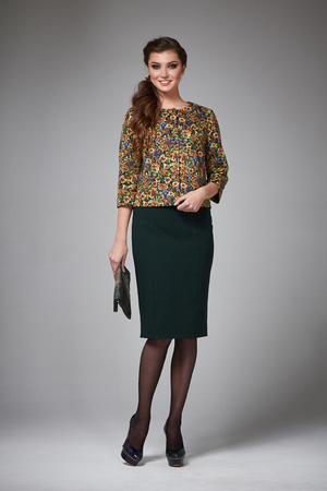 Beautiful young business woman with evening make-up wearing a skirt to the knee and a silk blouse with lace long sleeves and high-heeled shoes and a small black handbag, business clothes for meetingsの写真素材