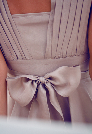 Detail on clothing or large silk chiffon bow on a beige dress with pleats and Valanio beautifully tied at the waist from behindの写真素材