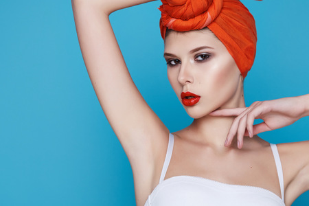 Beautiful young sexy girl with bright makeup perfect slim figure trained body and tan diet fitness club wearing a white stylish trendy top and orange headscarf sport underwearの写真素材