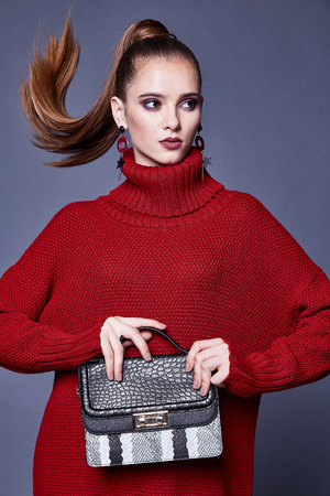 Fashion style woman perfect body shape brunette hair wear red knitted dress wool organic clothes sexy lady casual glamour accessory bag high heels shoes jewelry beautiful face makeup designer.の写真素材