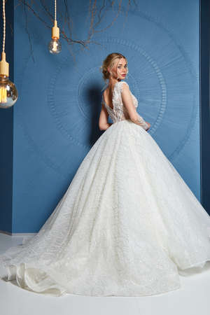 Beautiful tender young woman sexy brunette bride in a luxury white wedding dress lace chiffon Summer happiness awaits the groom before the wedding ceremony makeup accessory jewelry smile.の写真素材