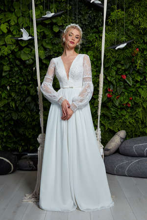 Beautiful tender young woman sexy brunette bride in a luxury white wedding dress lace chiffon Summer happiness awaits the groom before the wedding ceremony makeup accessory jewelry smile.の写真素材