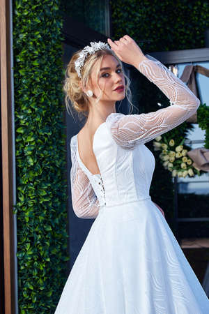 Beautiful tender young woman sexy brunette bride in a luxury white wedding dress lace chiffon Summer happiness awaits the groom before the wedding ceremony makeup accessory jewelry smile.の写真素材